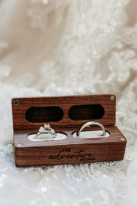 Bride and groom rings in their ring box on top of lace detail.